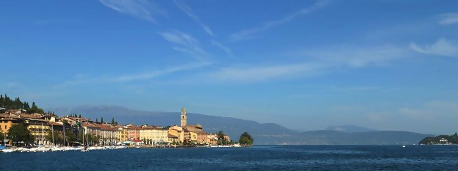 Trip Tirol beliebte Urlaubsziele am Gardasee -  Mit einer Fläche von 370 km² ist der Gardasee der größte See Italiens. Es liegt am Fuße der Alpen und erstreckt sich über drei Staaten: Lombardei, Venetien und Trentino. Die maximale Tiefe des Sees beträgt 346 m, er hat eine längliche Form und sein nördliches Ende ist sehr schmal. Dort ist der See von den Bergen der Gruppo di Baldo umgeben. Du trittst aus deinem gemütlichen Hotelzimmer und es begrüßt dich die warme italienische Sonne. Du blickst auf den atemberaubenden Gardasee, der in zahlreichen Blautönen schimmert - von tiefem Dunkelblau bis zu funkelndem Türkis. Majestätische Berge umgeben dich, während die Brise sanft deine Haut streichelt und der Duft von blühenden Zitronenbäumen deine Nase kitzelt. Du schlenderst die malerischen, engen Gassen entlang, vorbei an farbenfrohen, blumengeschmückten Häusern. Vereinzelt unterbricht das fröhliche Lachen der Einheimischen die friedvolle Stille. Du fühlst dich wie in einem Traum, der nicht enden will. Jeder Schritt führt dich zu neuen Entdeckungen und Abenteuern. Du probierst die köstliche italienische Küche mit ihren frischen Zutaten und verführerischen Aromen. Die Sonne geht langsam unter und taucht den Himmel in ein leuchtendes Orange-rot - ein spektakulärer Anblick.